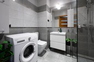 a bathroom with a washing machine and a toilet at City View Apartment in Iława