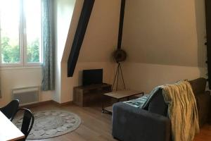 a living room with a couch and a tv at El Castillo, aux portes de Honfleur in Gonneville-sur-Honfleur