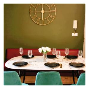 einen Tisch mit Weingläsern und eine Uhr an der Wand in der Unterkunft L'opale in Le Bourg-dʼOisans