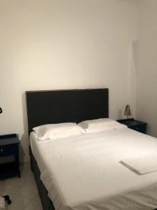 a bed with a black headboard and white sheets at Krinides Suites in Nerotriviá