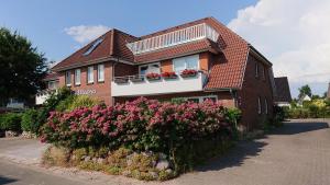 una casa de ladrillo con flores rosas delante de ella en Moderne Wohnung mit Privatpool en Büsum