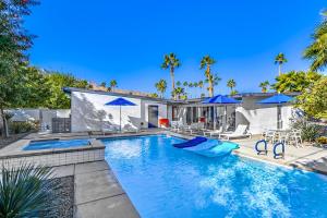 a swimming pool with blue umbrellas and a house at Riviera Palm Springs Permit# 2044 in Palm Springs