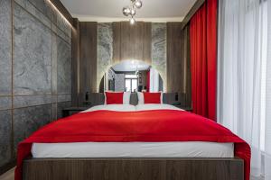 a bedroom with a large red bed with a red curtain at Apartamenty Park Residence by Nosalowy in Zakopane