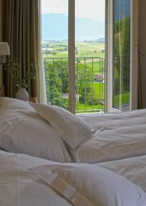 ein weißes Bett mit Blick auf ein Fenster in der Unterkunft Hotel Berghof Amaranth in Wilderswil