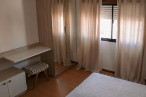 a bedroom with a bed and a desk and a window at Belo Apartamento Central Master Collection in Passo Fundo