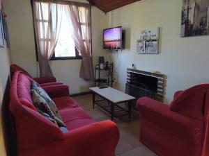 uma sala de estar com dois sofás vermelhos e uma televisão em Casa cómoda en Barra del Chuy, Uruguay em Barra del Chuy