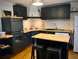 una cocina con armarios negros, fregadero y encimera en Maison de vacances La Valessoune en Valessard