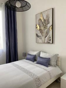 ein Schlafzimmer mit einem weißen Bett mit blauen Kissen in der Unterkunft Appartement Place des Promenades in Roanne