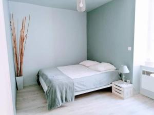 a white bedroom with a bed and a window at Appartement rouge avec jardin in Eymoutiers