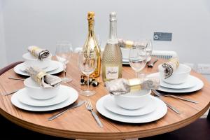 a wooden table topped with white plates and wine glasses at Wrexham Central Stay Apartment Seven in Wrexham