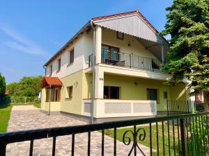 a yellow and white house with a black fence at Pine&Chill2 Apartments in Balatonalmádi
