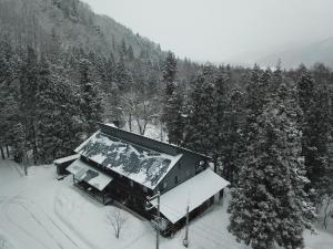 a house covered in snow in a forest at Bears Den Mountain Lodge in Hakuba +24 photos