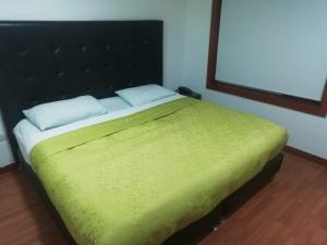 a bedroom with a bed with a green blanket at Embassy On Holidays in Bogotá