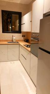 uma cozinha com armários brancos e um frigorífico de aço inoxidável em View Villas em Buraydah