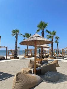 a sandy beach with a straw umbrella and palm trees at Villa Dafina in Donji Štoj