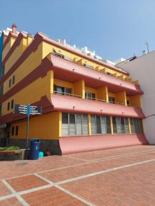 un edificio amarillo y rojo con un letrero en la calle en Apartamentos Maype Canteras, en Las Palmas de Gran Canaria