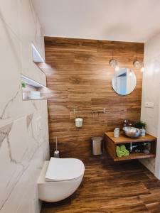 a bathroom with a white toilet and wooden walls at Viesu nams Kāpsargi in Ventspils