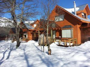 a wooden house with snow on the ground at Cabañas Maroni in Las Trancas