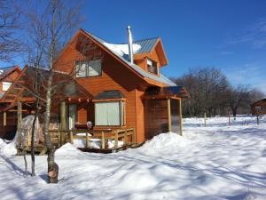 una casa de madera en la nieve con suelo cubierto de nieve en Cabañas Maroni, en Las Trancas