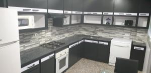una cocina con armarios y electrodomésticos en blanco y negro en Casa Erick, en Elche