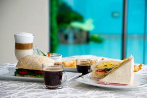 a table with two plates of sandwiches and two cups of coffee at Hotel Maresta Lodge - Hotel Asociado Casa Andina in Chimbote
