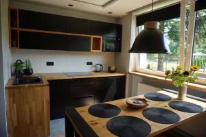eine Küche mit einem Holztisch und schwarzen Schränken in der Unterkunft APARTAMENTY JEDYNE TAKIE.... in Ustroń
