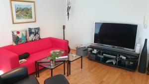 a living room with a red couch and a flat screen tv at Vanny's Guesthouse in Ytri-Njarðvík