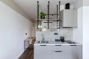 a kitchen with white cabinets and a sink at The Athenians Art Apartments in Athens