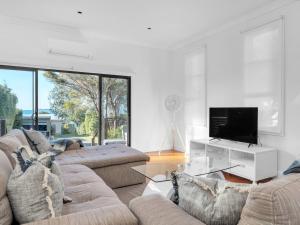 a living room with two couches and a flat screen tv at Neptune Hyams Beach in Hyams Beach