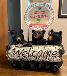a group of three bears holding a welcome sign at Bears Den Mountain Lodge in Hakuba