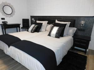 Una cama grande con almohadas blancas y negras. en HOTEL TERRA GALEGA MEIGA, en Monforte de Lemos