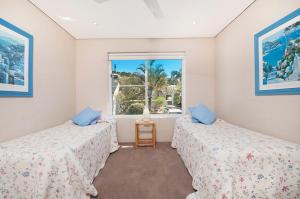 two beds in a room with a window at Quarterdeck 20 in Lennox Head