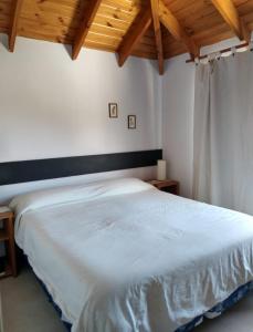 Una cama blanca en un dormitorio con techos de madera. en Departamento M&M en San Martín de los Andes