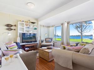 a living room with couches and a tv and a window at Noddys Riverside in Greenwell Point