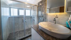 een badkamer met een wastafel en een glazen douche bij Midpoint Suites in Fethiye