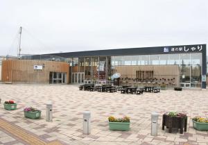 a building with tables and potted plants in front of it at Okhotsk House Shari in Shari