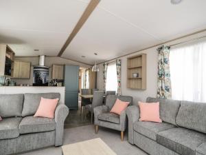 a living room with two gray couches and pink pillows at Burlees Nest in Cockermouth