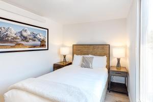 a white bedroom with a bed and two lamps at Fish Creek Point in Wilson