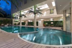 a large pool in a building with palm trees at Sun Boutique Hotel in Kuta