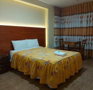 ein Schlafzimmer mit einem Bett mit einer gelben Decke darauf in der Unterkunft Lembranças Hotel in Huánuco