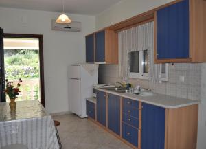 een keuken met blauwe kasten en een witte koelkast bij Beachfront House Tolis - Pelekas Beach in Pelekas
