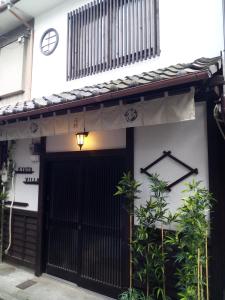 een huis met een zwarte poort en een klok aan de muur bij Kyoto Villa Fuka in Kyoto