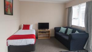 a bedroom with a bed and a couch and a television at Fiesta Court Motel in Whanganui