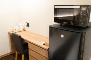 a microwave sitting on top of a refrigerator next to a desk at Chiyokura HOTEL SHUKU Nagoya in Nagoya