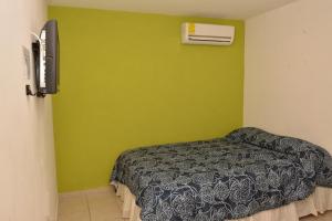 a bedroom with a bed and a green wall at Hotel Bugambilias in Ciudad Obregón