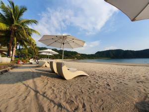 uma fila de cadeiras e um guarda-sol numa praia em Pico de Loro Staycation (3 beds- 6 pax) em Nasugbu