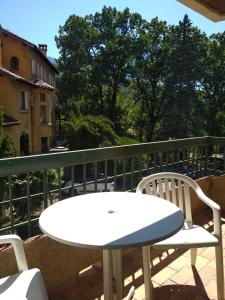 - Balcón con mesa blanca y 2 sillas en Hotel Le Mas Fleuri, en Vernet-les-Bains