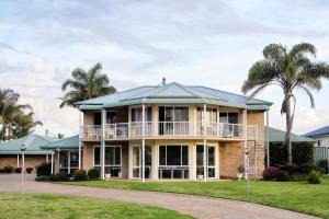 a large house with palm trees in the background at Harbourview House in Bermagui