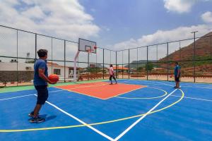 Un gruppo di uomini che giocano a basket su un campo di La Palm by StayVista - Mountain-view villa, boasting a spacious pool, Gym, Indoor games, Basketball court & A lush lawn with a gazebo a Lonavala