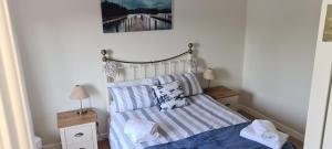 a small bedroom with a bed with striped sheets at Cromlech Cottage in Portnoo